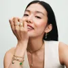 A woman wearing jewelry, including rings, earrings, a necklace, and bracelets. Podgląd zdjęcia produktu