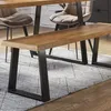 A wooden bench with black metal legs is placed on a rug in front of a dining table and chairs. Náhled obrázku produktu