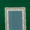 Christmas lights are strung around a window on a green shingled house. Anteprima dell’immagine prodotto