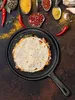 A top-down view of a quesadilla in a cast iron pan, surrounded by various spices and chili peppers. Produktbild-Vorschau