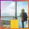 A person with a backpack and a yellow suitcase stands at an airport window, looking at an airplane. Anteprima dell’immagine prodotto