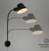 A black adjustable wall lamp is shown on a light gray background, with ghosted images of the lamp in different positions. Produktbild-Vorschau
