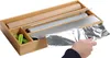 A hand is pulling aluminum foil from a bamboo dispenser that holds rolls of parchment paper, plastic wrap, and aluminum foil. Produktbild-Vorschau