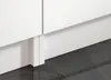 A close-up view of the base of white kitchen cabinets and the dark tiled floor. Náhled obrázku produktu
