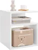 A white cube-shaped side table with two open shelves. The top shelf holds a small white bunny figurine, a white mug on a wooden coaster. The lower shelf contains a brown fabric storage box with a cartoon rabbit face. Produktbild-Vorschau