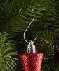 A close-up shot of a red glittery star-shaped Christmas ornament hanging on a green artificial Christmas tree. Produktbild-Vorschau