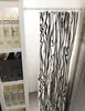 A white shelf unit with storage boxes and binders next to a black and white striped curtain hanging from a tension rod. Produktbild-Vorschau