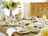 A beautifully set breakfast table with a floral arrangement, porcelain tableware, and food items. Produktbild-Vorschau