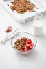 A bowl of granola with strawberries and a glass of milk on a white wooden table. Podgląd zdjęcia produktu