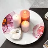 A decorative plate with lit candles and a burnt matchstick. Voir les images du produit