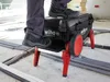 A person is standing on a tool box with wheels in a construction environment. Produktbild-Vorschau