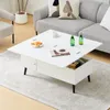 A white lift-top coffee table with storage is shown in a living room setting, with a sofa and armchair in the background. Produktbild-Vorschau