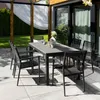An outdoor patio setting with a dining table and chairs, surrounded by greenery and a pergola. Náhled obrázku produktu