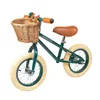 A dark green balance bike with a wicker basket and brown leather accents, shown against a white background. Produktbild-Vorschau