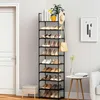 A tall, black, multi-tiered shoe rack filled with shoes, placed next to a white door and a small side table with a vase and books. Produktbild-Vorschau