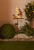A solar-powered garden stake with a rain gauge and LED lights, set in a garden at dusk. Anteprima dell’immagine prodotto