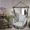 A hanging chair is shown in a living room setting, with a sofa and plants in the background. Produktbild-Vorschau