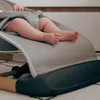 Close-up of a baby's legs and feet in a grey baby bouncer. Podgląd zdjęcia produktu