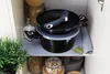 Pots and pans are neatly stacked on a shelf in a kitchen cabinet. Podgląd zdjęcia produktu