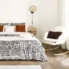 A bedroom scene with a bed, chair, and bedside table. Produktbild-Vorschau