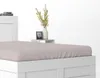 A close-up view of a white bed frame with a pink fitted sheet. Produktbild-Vorschau
