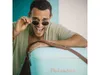 A man wearing sunglasses leans over a turquoise cooler. Podgląd zdjęcia produktu