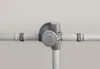 A close-up view of a gray umbrella pole connector with a logo on it, attached to two horizontal poles. Produktbild-Vorschau