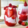 A close-up of a strawberry and cream dessert in a glass, with more desserts and strawberries in the background. Náhled obrázku produktu