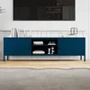 A dark blue metal TV stand with doors and an open shelf, placed on a wooden floor in front of a tiled wall. A television is mounted on the wall above the stand. Anteprima dell’immagine prodotto