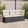 A dark gray rattan sofa with beige cushions is placed on a paved patio in front of a wooden fence. String lights are visible overhead. Podgląd zdjęcia produktu