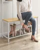 A woman sitting on a shoe rack bench, putting on a shoe. Náhled obrázku produktu