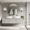 A modern bathroom with a double vanity, large round mirror, and two white bathrobes hanging. Podgląd zdjęcia produktu