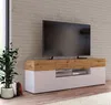 A modern TV stand with a large television on top, placed in a room with a brick wall. Produktbild-Vorschau
