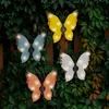 Four solar-powered butterfly lights are attached to a fence covered in greenery. Podgląd zdjęcia produktu