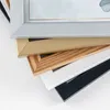 A stack of different picture frames, each with a different color and material, are shown from a close-up perspective. Produktbild-Vorschau