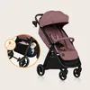 A pink baby stroller is shown against a light beige background. A circular inset highlights the stroller's storage basket, which contains toys and has a water droplet icon indicating water resistance. Produktbild-Vorschau