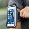 A person wearing a grey t-shirt and a running armband with a smartphone inside, outdoors. Produktbild-Vorschau