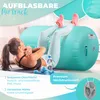 A woman is doing sit-ups on a yoga mat next to a large, teal-colored inflatable air roll. There are dumbbells and a water bottle nearby. The background is a bright, abstract design with text overlays. Produktbild-Vorschau