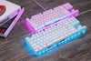 Two white mechanical keyboards with RGB lighting are displayed on a wooden surface, next to a stack of books. Produktbild-Vorschau
