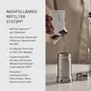 A hand is pouring dark granules from a small white packet into a stainless steel water filter device. The text on the left provides details about the refillable filter system. Náhľad obrázku produktu