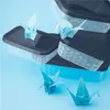 Several clear plastic food storage containers are stacked, with origami cranes placed on top of some of them and on the blue surface in front. Náhľad obrázku produktu
