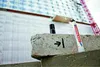 A marker pen is placed on a concrete block with markings, with a building under construction in the background. Produktbild-Vorschau