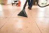 A person is using a wet/dry vacuum cleaner on a tiled floor. Náhled obrázku produktu