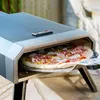 A pizza is being prepared in a gas pizza oven outdoors. Produktbild-Vorschau