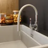 A close-up view of a beige kitchen faucet with a flexible spout over a light gray sink. Anteprima dell’immagine prodotto