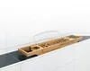 A wooden bath caddy with a metal book holder and glass holder rests on the edge of a bathtub. Produktbild-Vorschau