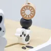 A close-up of wooden toy beads and a duck figure on a wooden surface. Produktbild-Vorschau