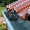 A black gutter guard is placed in a rain gutter, with roof tiles visible above. Náhled obrázku produktu