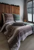 A cozy bedroom scene with a bed dressed in patterned bedding, a window showing a snowy landscape, and decorative lights. Produktbild-Vorschau