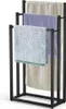A black metal towel rack with three bars, holding three different colored towels. Produktbild-Vorschau